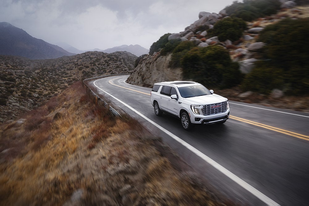 White Yukon driving through Mountains